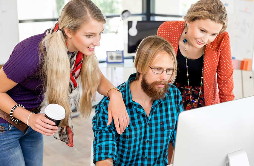 three business people looking at computer - woman resting arm on man's shoulder