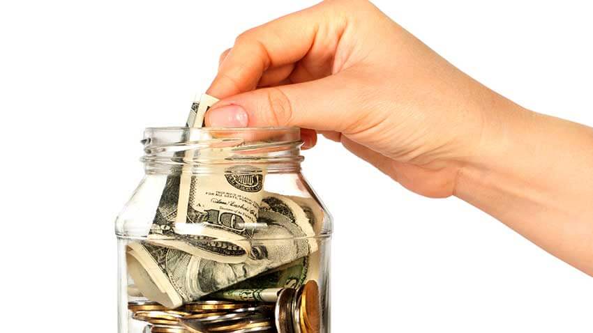 hand putting money in a jar