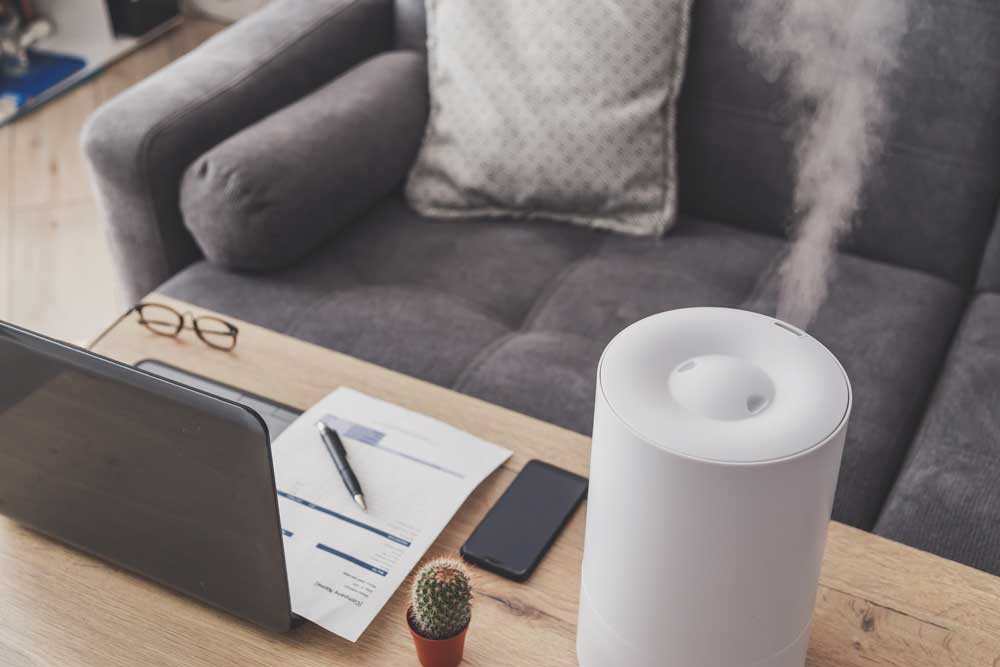 humidifier on table next to laptop in front of a couch