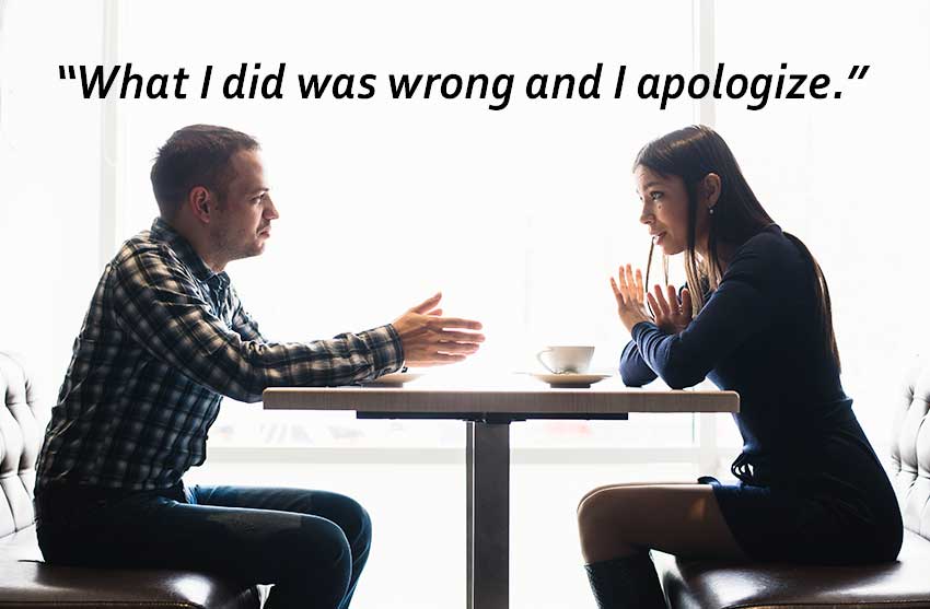 two clenched fists on table in front of a laptop